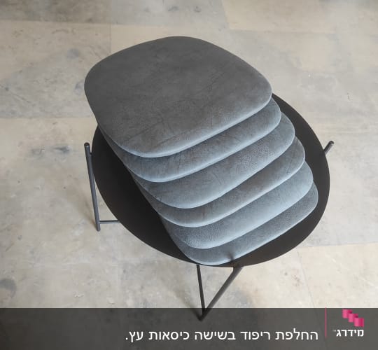 כריות מרופדות אפורות מונחות על שולחן עגול שחור
